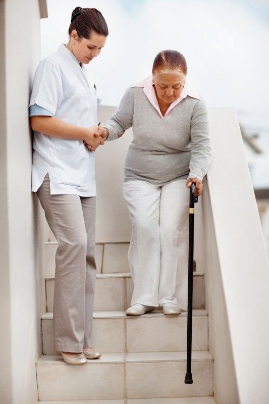 Woman helping elderly woman down steps | Neighborly Home Care Offers Skilled Elder Care Services in PA and DE