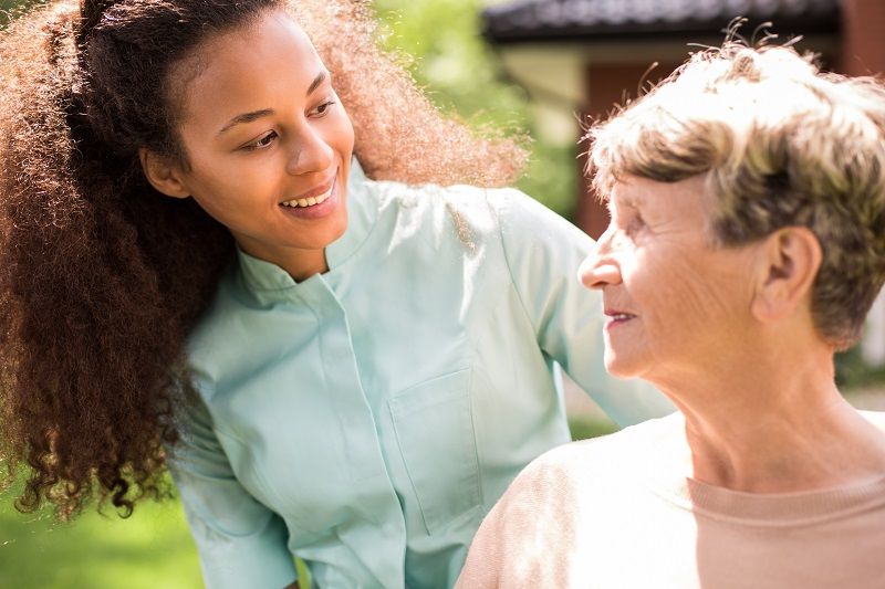 Caregiver serving senior woman a tray of food | senior home care in Wilmington | Neighborly Home Care