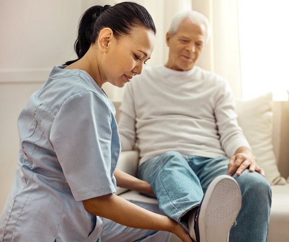 senior woman in bed being assisted by caregiver | Recovery Care can include 24 hour home care services or part time assistance | Neighborly Home Care