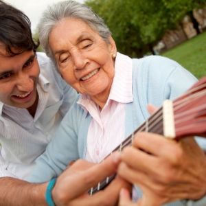 Caregiver playing guitar with elderly woman | elder care services | Neighborly Home Care