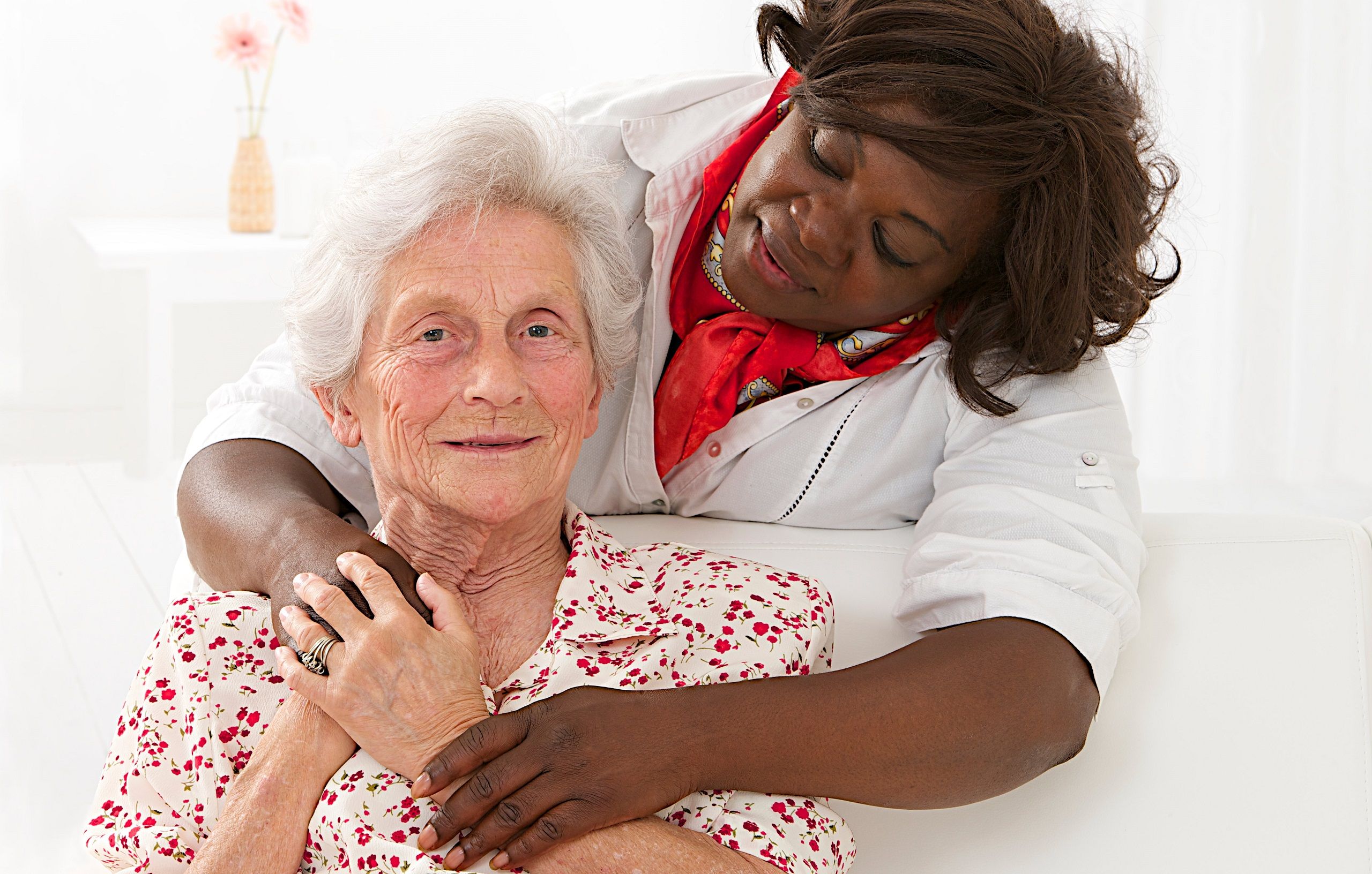 Caregiver in blue scrubs smiling and reaching out to senior woman | Caregiver Agency | Neighborly Home Care