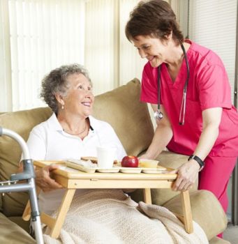 Caregiver giving senior food tray | Home health care agency services including Senior Care and Disability Care | Neighborly Home Care