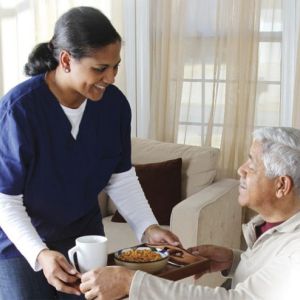 Caregiver handing elderly man tray of food | elder home care services | Neighborly Home Care