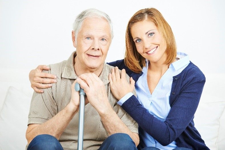 Caregiver sitting with elderly gentleman holding a cane | Senior Care Services | Neighborly Home Care