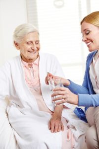 Senior woman adult woman holding glass of water and pill | technology is changing senior care | Neighborly Home Care