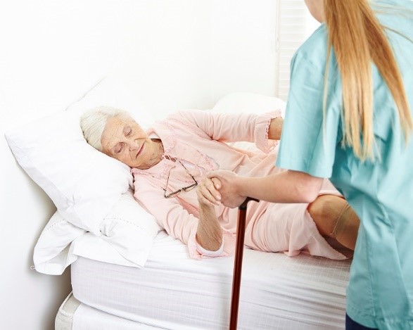 nurse helping elderly woman out of bed