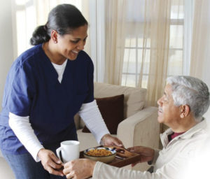 Caregiver giving tray of food to elderly man | benefits of in home care | Neighborly Home Care