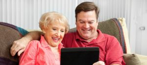 Adult son and elderly mother looking at a tablet together | Telemedicine Can Help Seniors | Neighborly Home Care