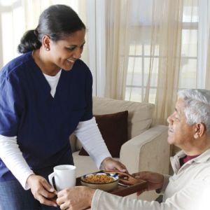 Caregiver handing elderly man tray of food | elder home care services | Neighborly Home Care